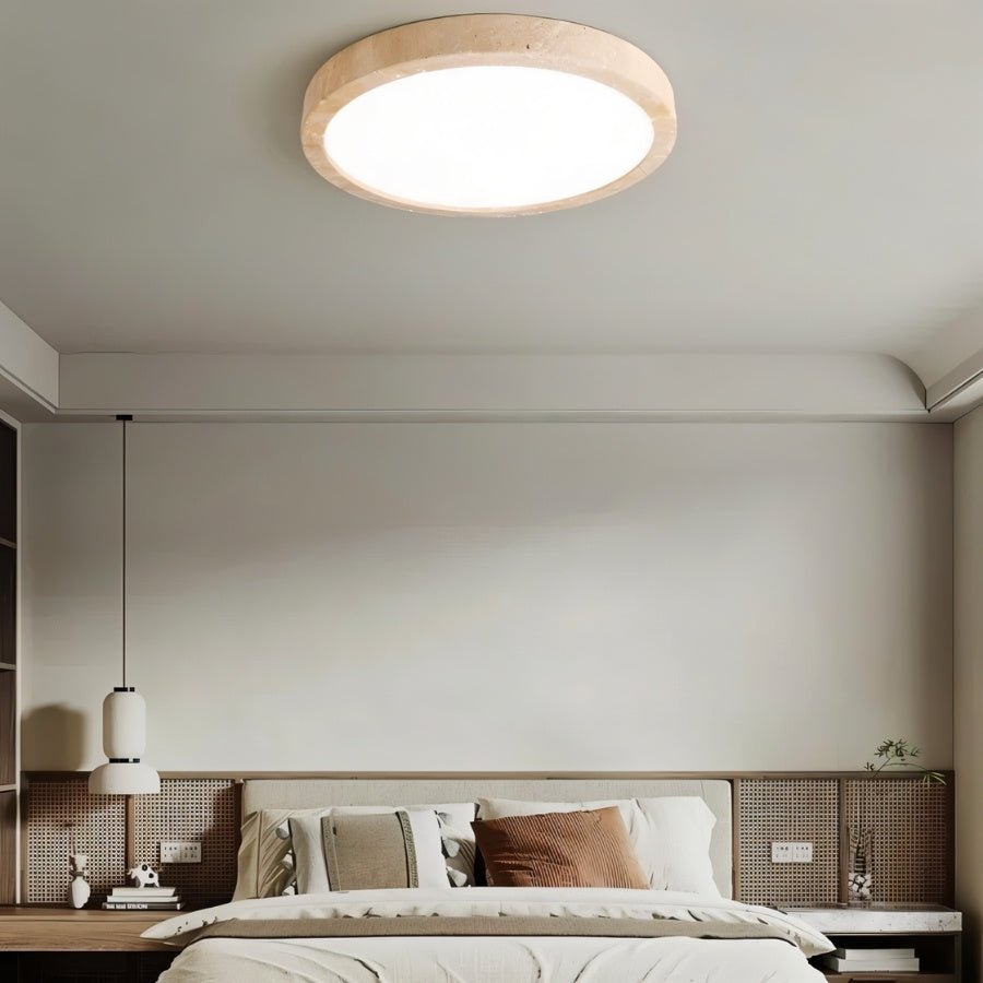 "A minimalist, natural travertine Richna ceiling light centered in a modern bedroom, providing soft, uniform illumination."
