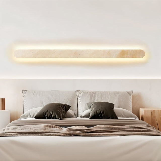 "Minimalist travertine wall light installed above a bed, creating a warm and inviting atmosphere"