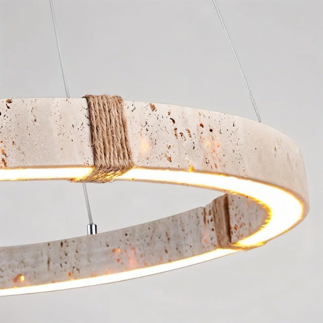 "Close-up of a circular travertine chandelier with an integrated LED strip and hemp rope detailing, showcasing its raw, textured aesthetic."