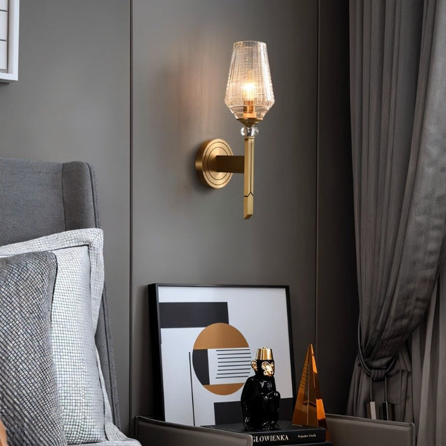 "Modern wall lamp with copper base, gold finish, and textured glass shade providing a soft glow in a contemporary bedroom setting."