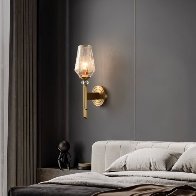 "Modern wall lamp with copper base, gold finish, and textured glass shade, providing a soft glow in a contemporary bedroom setting."
