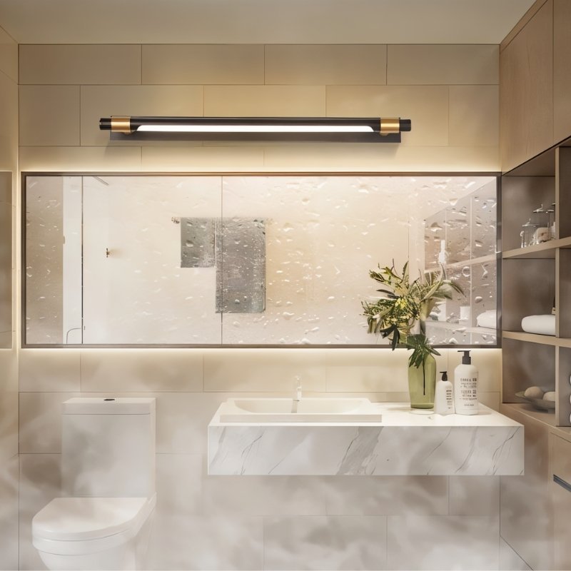 "A modern black and gold wall lamp with a sleek, adjustable cylindrical light bar mounted above a large rectangular bathroom mirror in a contemporary bathroom setting."