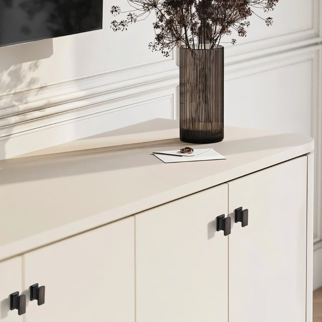 "Black zinc alloy knobs with angular design on a white cabinet with a curved countertop."
