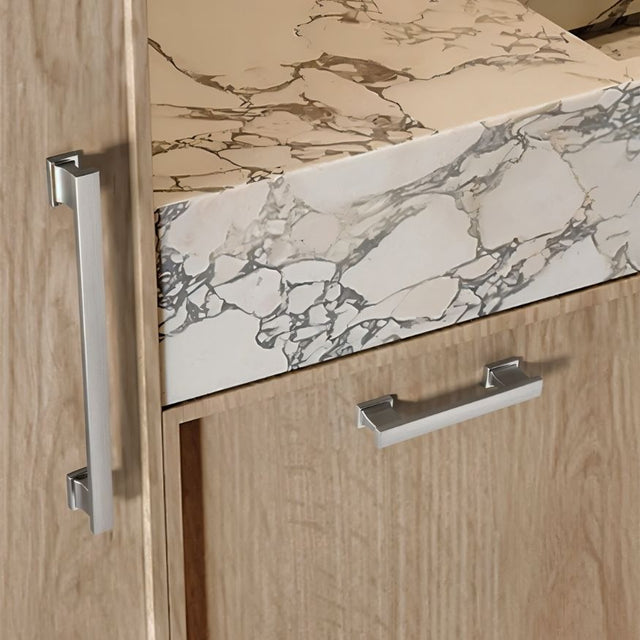 "Silver zinc alloy pull bars with angular design on light wood cabinets with a marble countertop."