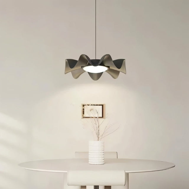 "Sculptural pendant light with a wave-like iron frame and acrylic diffuser hangs above a modern dining table, casting a balanced glow."