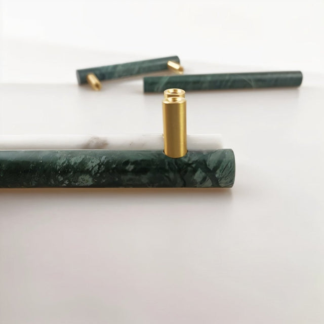 "Arrangement of marble and brass pull bar components, showcasing the cylindrical design and materials."