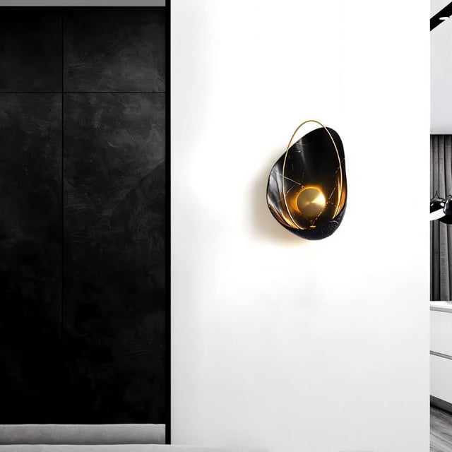 "Modern black resin wall lamp with gold sphere and metal hoop, mounted on a white wall in a contemporary setting."