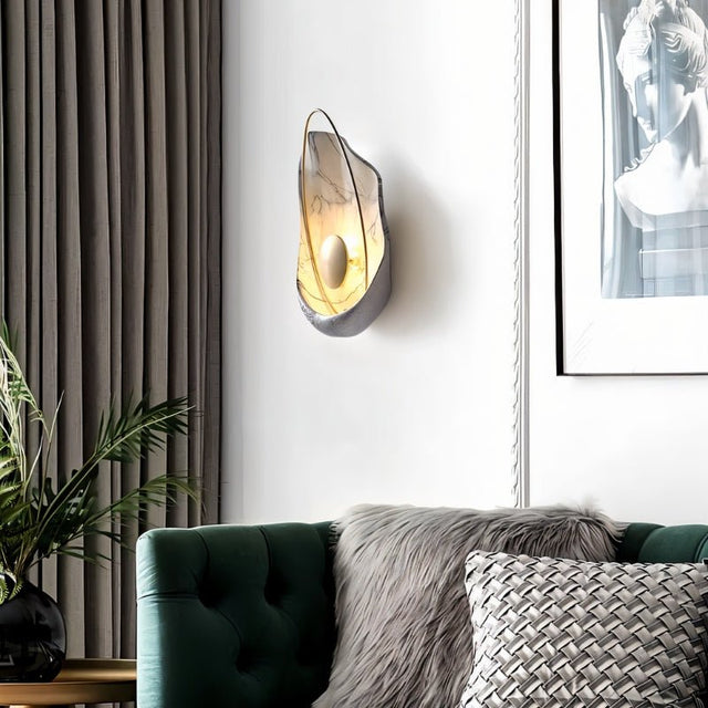 "Modern white resin wall lamp with gold sphere and metal hoop, mounted above a sofa in a living room."