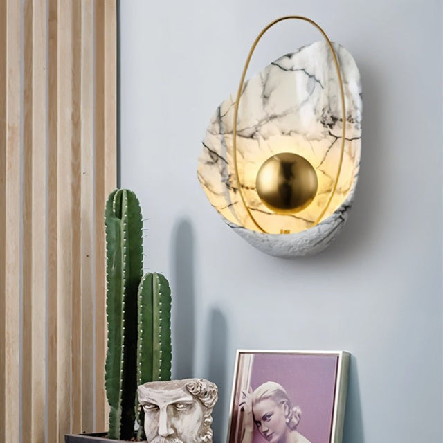 "Modern white resin wall lamp with gold sphere and metal hoop, illuminating a living room."