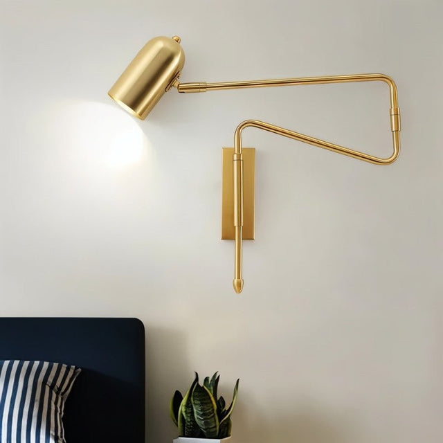 "Gold adjustable arm bedside reading lamp mounted on a bedroom wall."