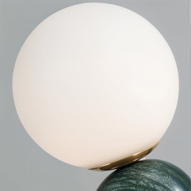 Close-up of Sibwa Table Lamp's white glass globe and green marble base with brass accent, emphasizing premium lighting design.