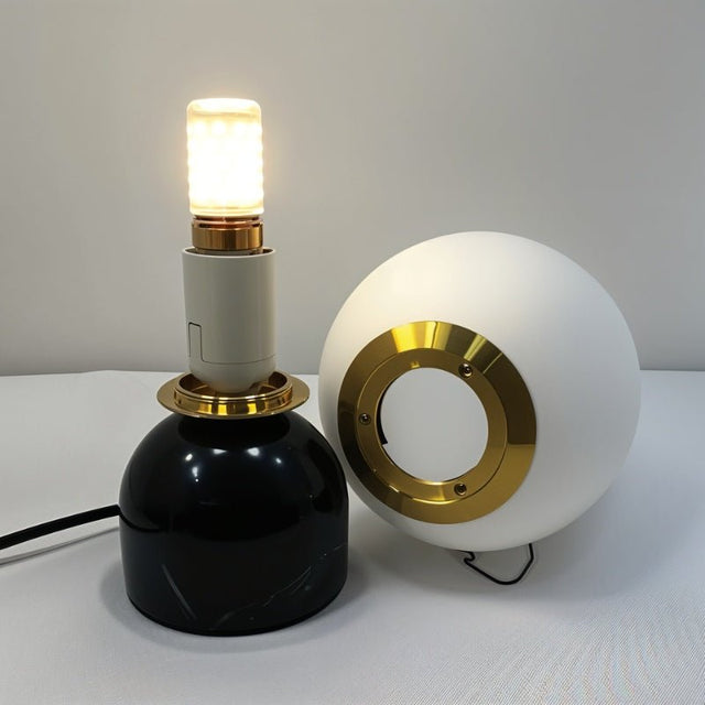 Disassembled Sibwa Table Lamp showing LED bulb, brass fittings, and black marble base, highlighting product construction details.