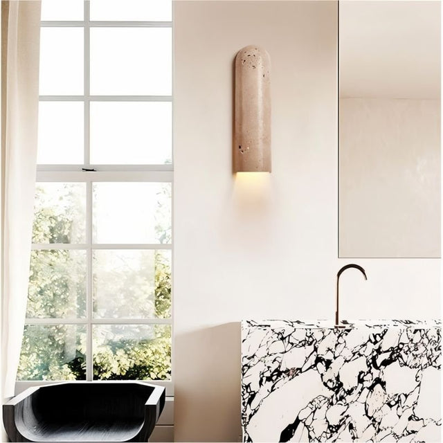 "Solon travertine wall lamp installed in a modern bathroom, highlighting its elegant design and natural texture, casting a warm, ambient light."
