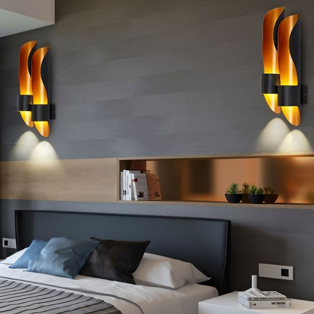"Pair of modern flame-inspired wall lamps with a dual-tone metal finish flanking a headboard in a contemporary bedroom."