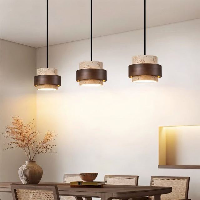 "Group of three modern stone and wood cylindrical pendant lights hanging over a dining table."