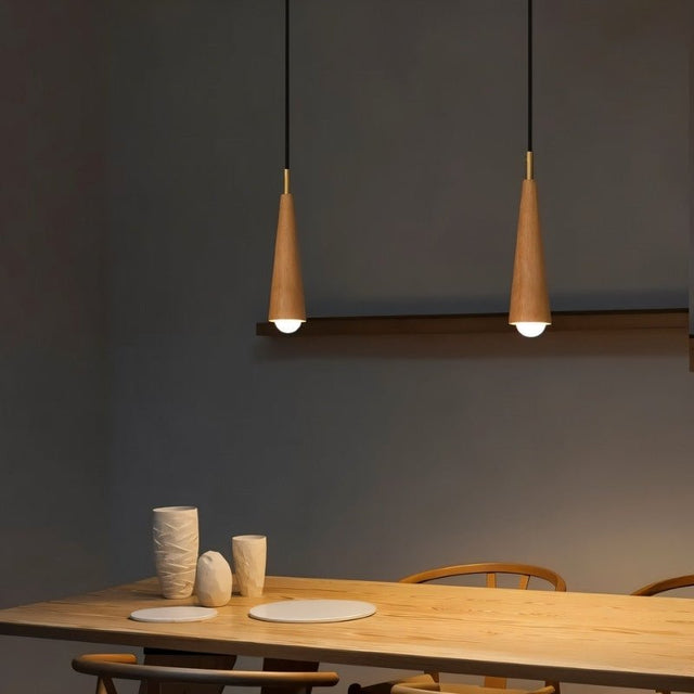 "Pair of wooden pendant lights with copper accents illuminate a dining room table."