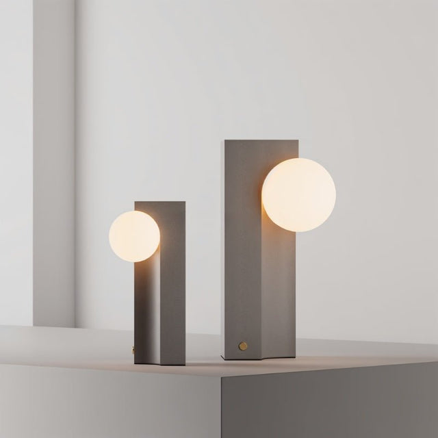 Two sizes of Teral Table Lamp with glowing globes on concrete bases, offering versatile ambient lighting for modern spaces.