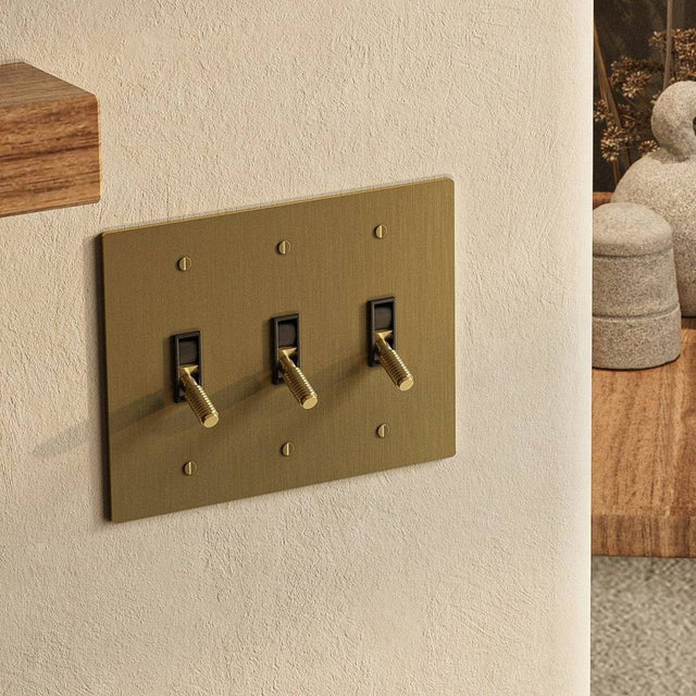 Brushed brass triple gang The Brass Toggle Switch (1 to 5 Gang) - Open Box mounted on a neutral wall, perfect for elegant home lighting upgrades.