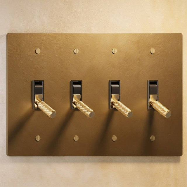Four-gang The Brass Toggle Switch (1 to 5 Gang) - Open Box with knurled toggles on a brushed brass plate, ideal for multi-light room configurations.