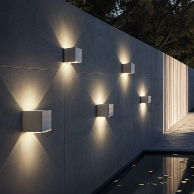 "Tine Wall Lamps installed in a row on a modern outdoor wall, casting ambient light upward and downward, made from durable gypsum and aluminum."