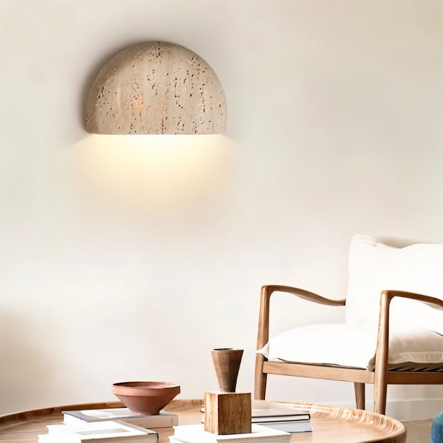 "A minimalist, semi-circular travertine wall lamp enhancing a modern living room with its soft glow and organic texture."