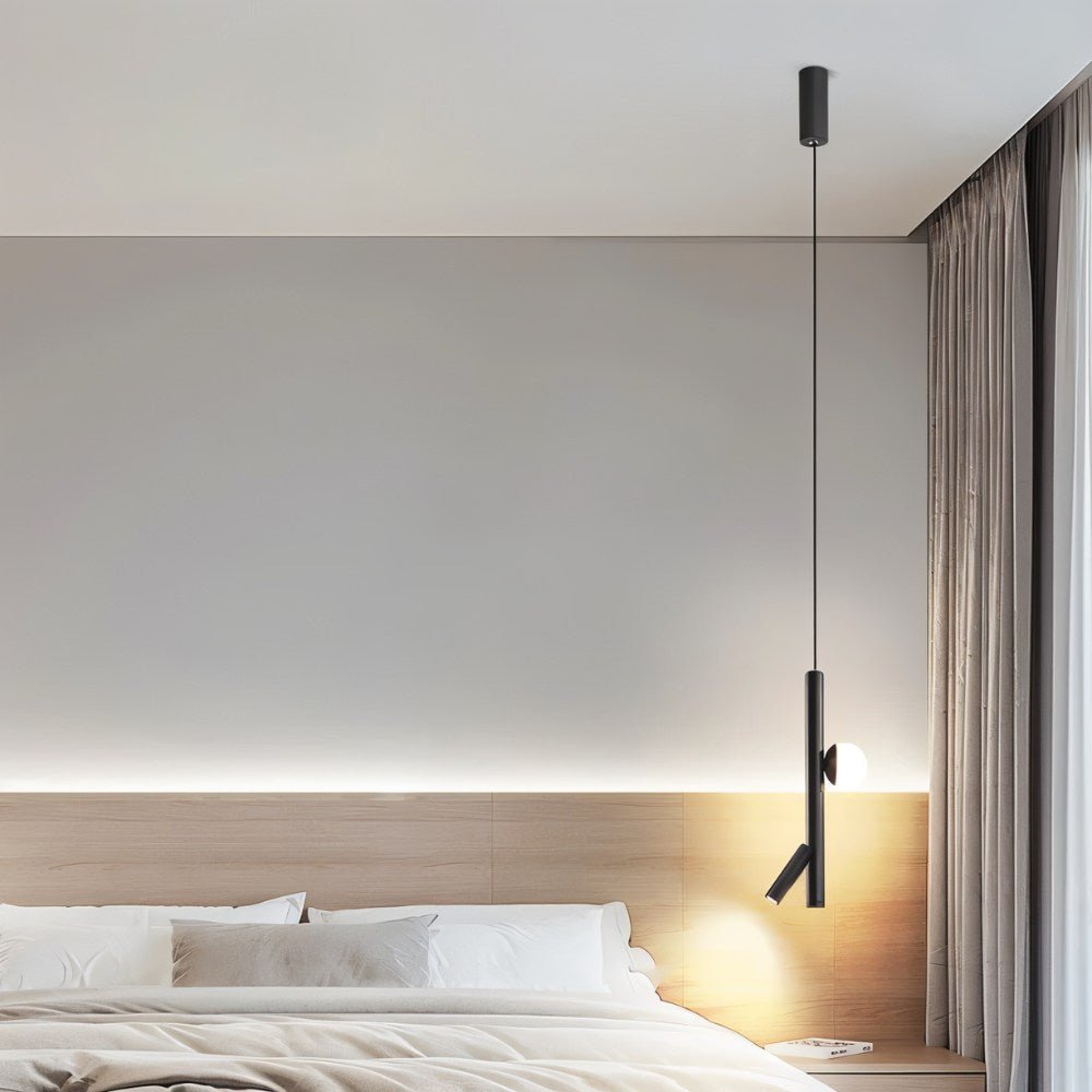 "A minimalist modern bedroom featuring a sleek iron and acrylic pendant light with cylindrical rods and a glowing orb accent, hanging above a wooden headboard."