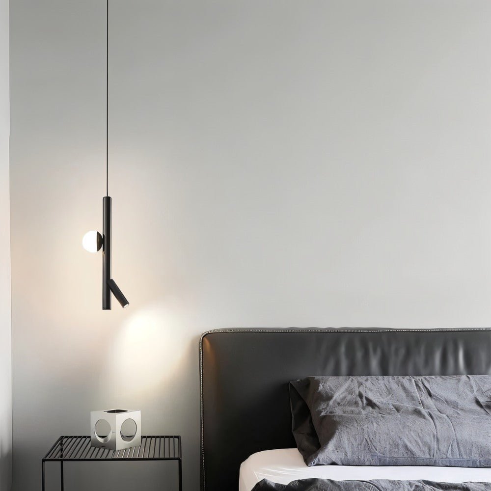 "A sleek, iron and acrylic pendant light with cylindrical rods and a glowing orb accent hangs in a modern bedroom at night, casting light on a side table and bed."