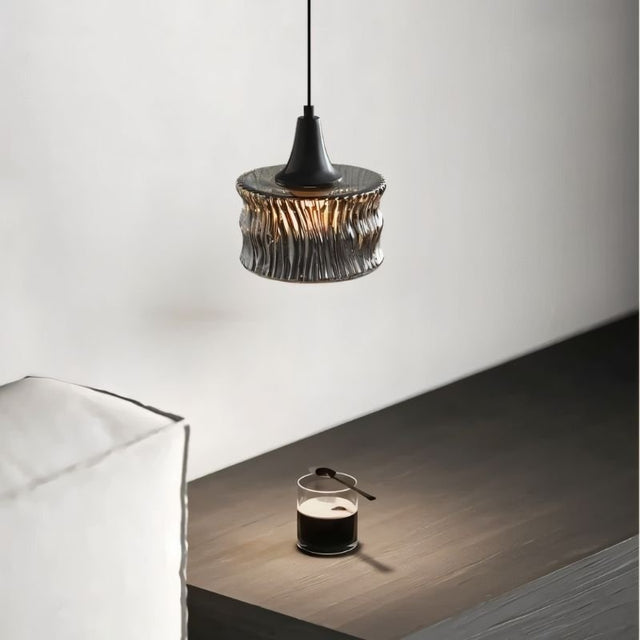 "A pendant light with a rippled glass shade in a modern interior setting."