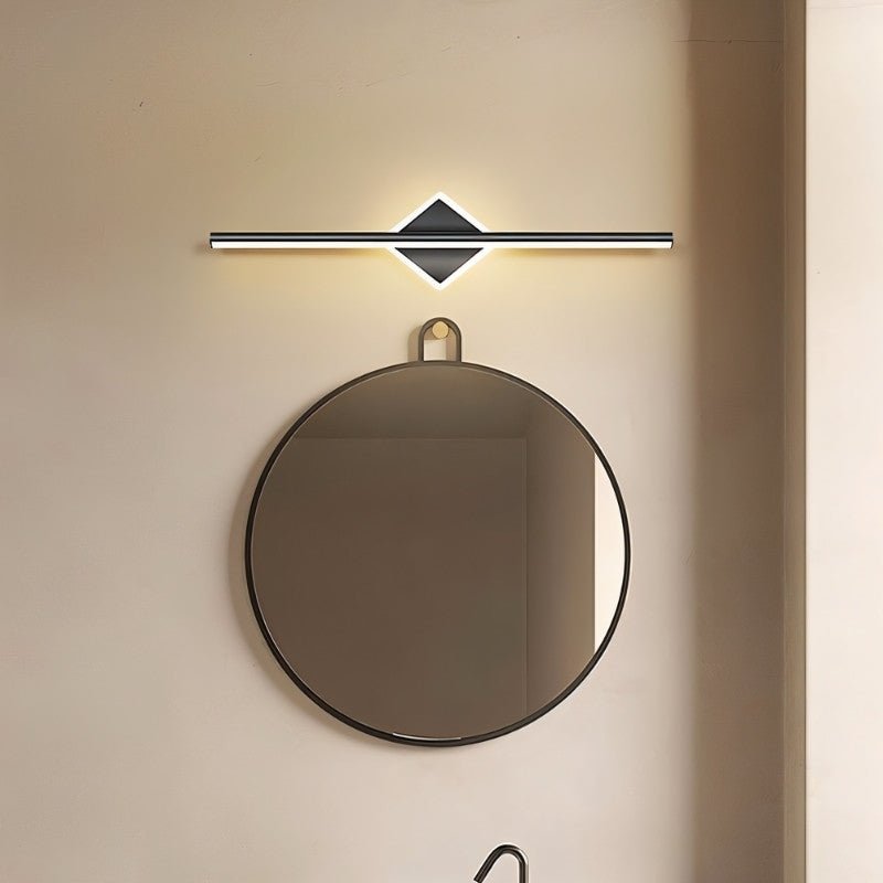 "A modern black wall lamp with a diamond-shaped base and horizontal bar, mounted above a round mirror with a strap in a contemporary bathroom."