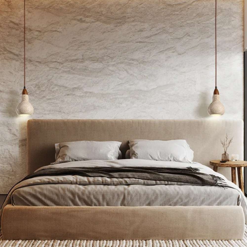"Two travertine pendant lights hanging on either side of a bed in a bedroom."