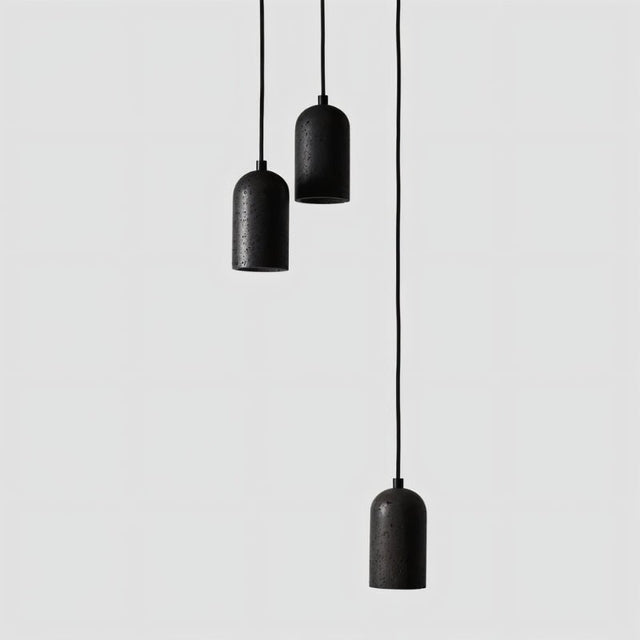 "Arrangement of modern cylindrical pendant lights crafted from black travertine, showcasing their natural, textured surface and contemporary design."
