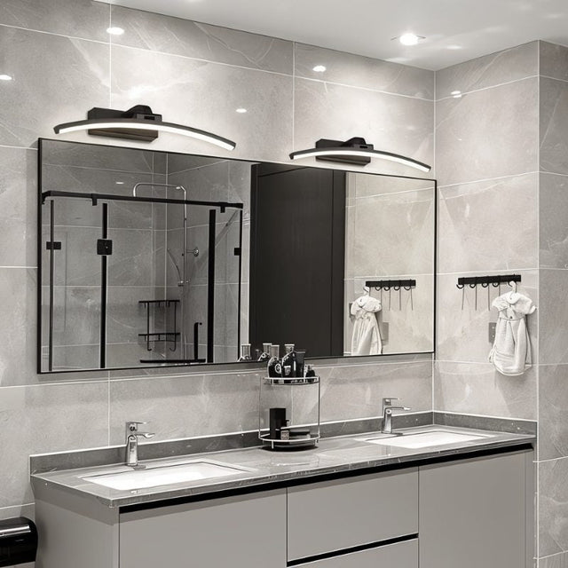 "Two modern, curved LED wall lamps illuminating a double sink bathroom vanity with mirrors."