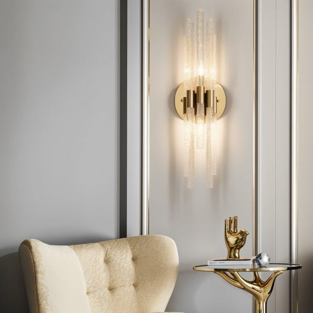 "A modern brass wall sconce with textured glass rods mounted on a panelled wall."