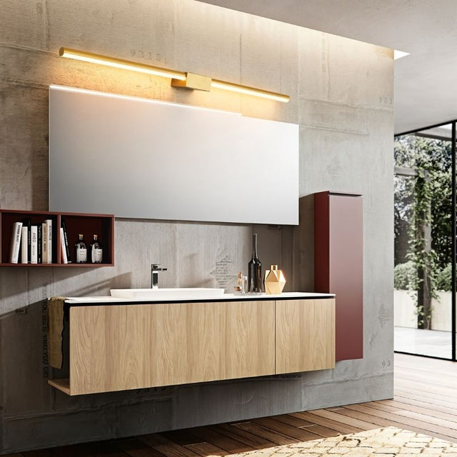 "Modern bathroom featuring a linear Zanal wall lamp in gold, providing soft illumination above a wood vanity with a minimalist design."