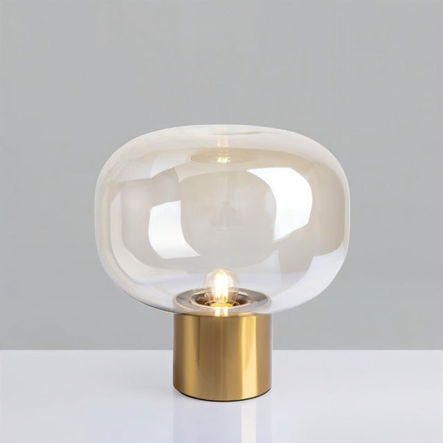 "Zareen table lamp with a clear glass shade and sleek aluminum base, providing soft, diffused lighting for any space."