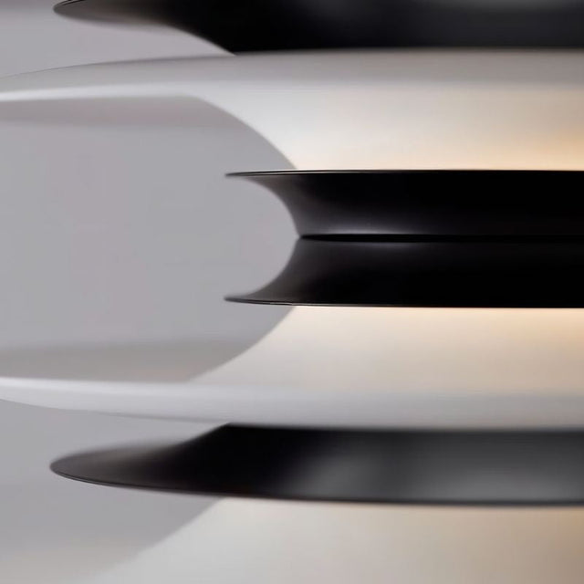 "A close-up view of a modern pendant light showing the layered discs in black and white, highlighting the textured design and soft illumination."