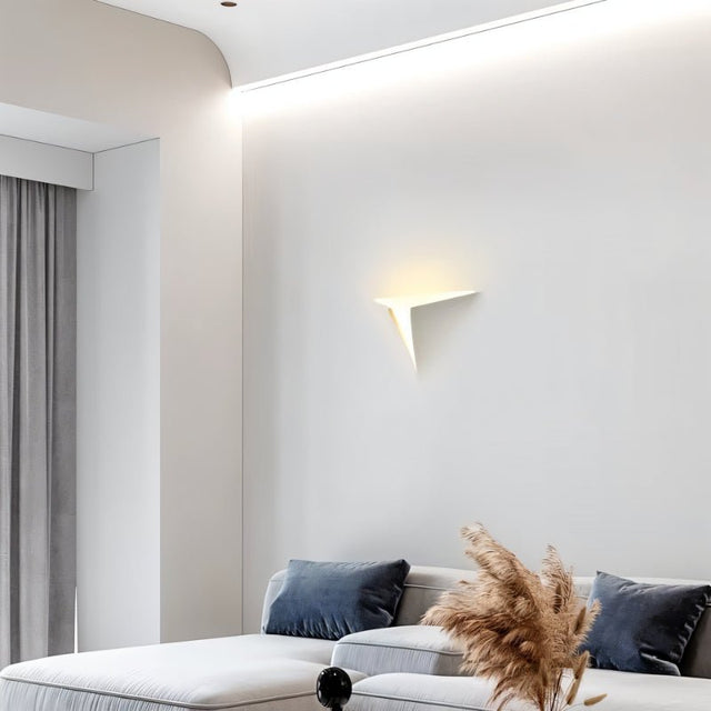"A lit white trimless wall light with a geometric design on a white wall above a couch in a modern living room."