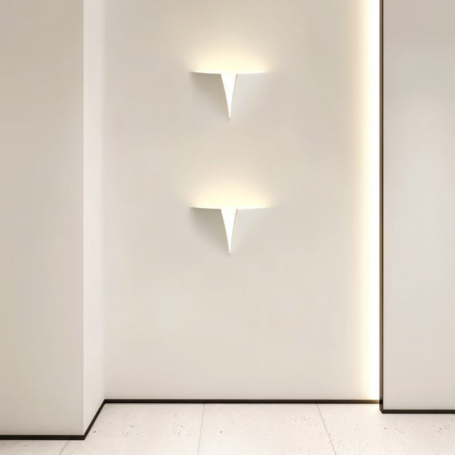 "Two lit white trimless wall lights with a geometric design on a white wall in a modern hallway."
