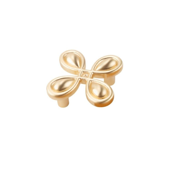 "A brushed gold, clover-shaped knob made of zinc alloy, isolated on a white background."