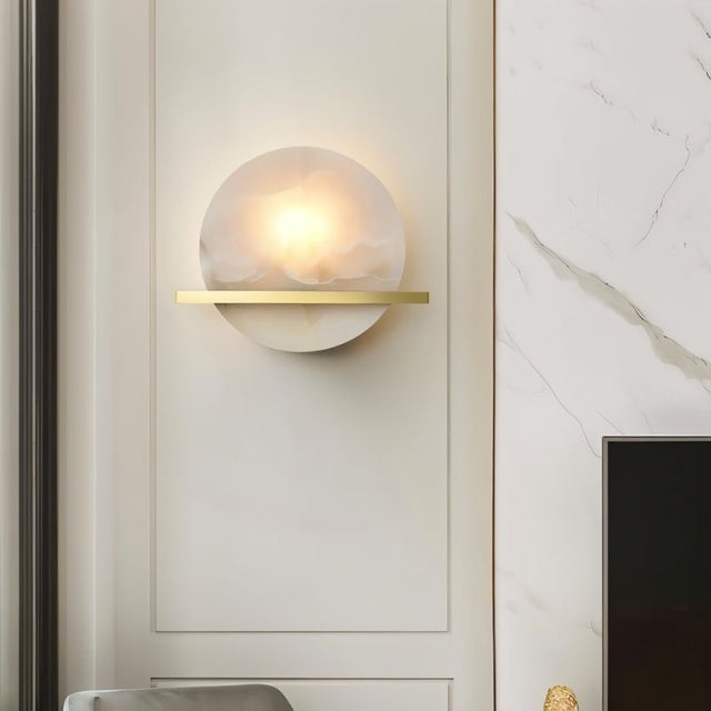 "Round alabaster wall lamp with brass details, illuminating a modern luxury interior with a soft, warm light."