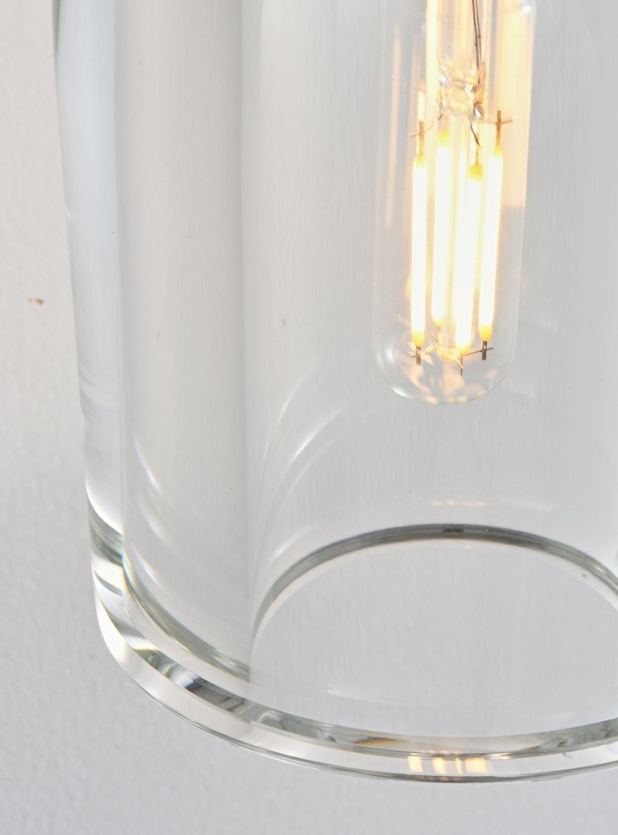 "Close-up detail of a clear glass shade, showing its shape and the illuminated bulb inside."