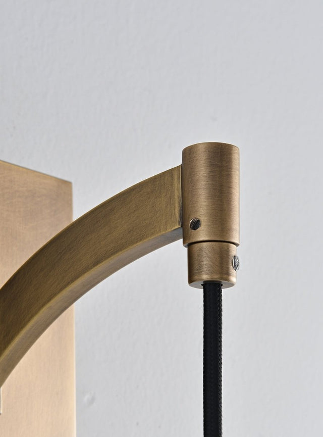 "Close-up detail of a modern brass wall lamp arm, showing the curved design and connection to the base."