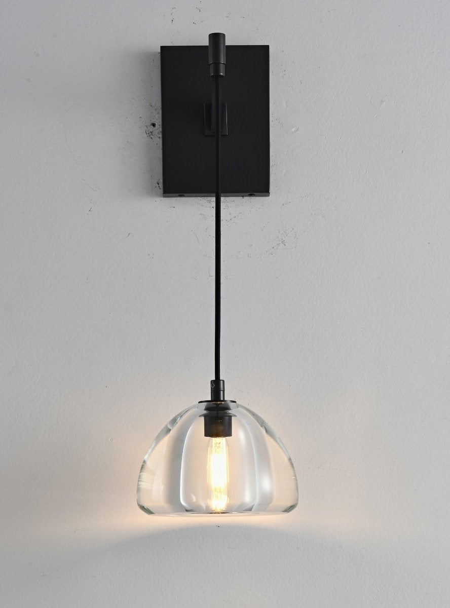 "A modern brass wall lamp with a clear glass shade, blending elegance and minimalist design with a curved arm and rectangular base."