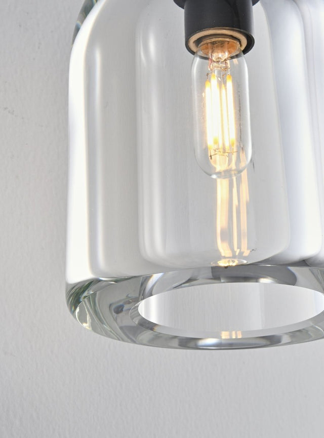 "Close-up detail of a modern wall lamp with a clear glass shade, showing the bulb and design."