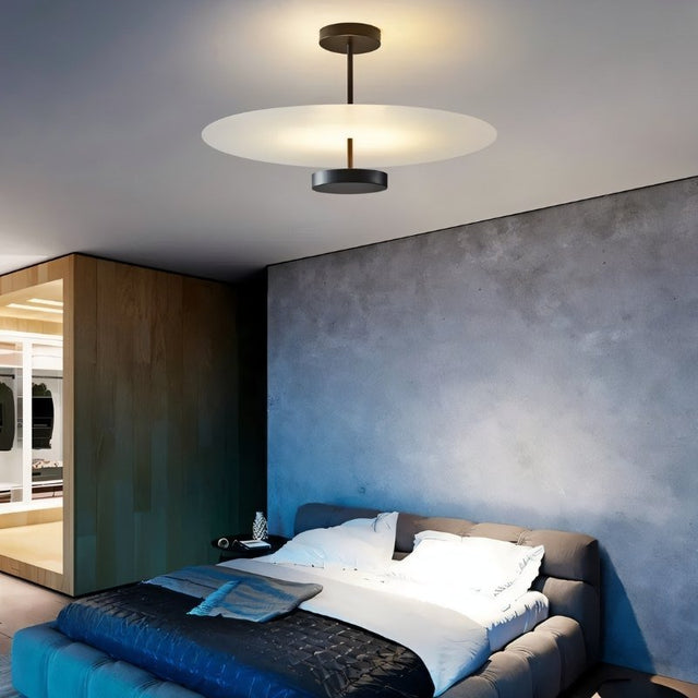 "A minimalist ceiling light with a circular acrylic diffuser and a sleek metal frame illuminating a modern bedroom."