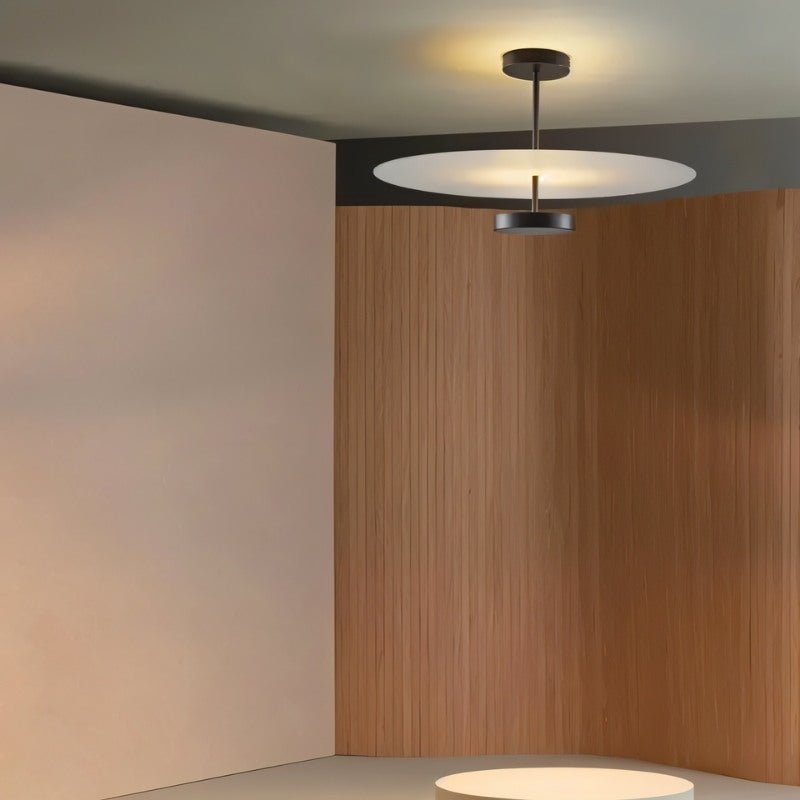 "A minimalist ceiling light with a circular acrylic diffuser and a sleek metal frame in a modern living room setting."