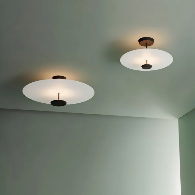 "Pair of minimalist ceiling lights with circular acrylic diffusers and sleek metal frames, mounted on a light green ceiling."