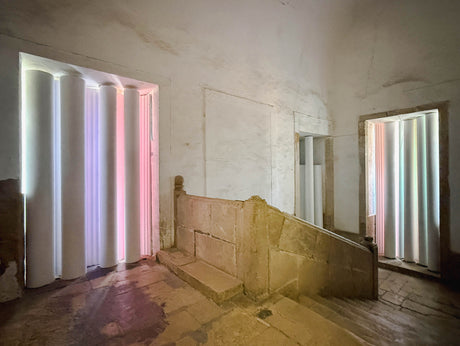 Photochromic Organ, designed by Alexandra Barker, FAIA, and Reid Freeman, AIA, transforms the historic stair landing at the Monastery of Santa Clara-a-Nova in Coimbra, Portugal with illuminated cylindrical light elements for ANOZERO'26, Bienal de Coimbra.