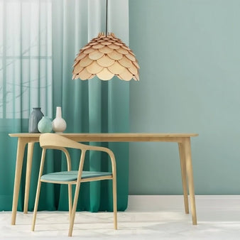 "The Atal wooden pendant lamp hangs above a modern dining table with a light wood finish and a chair with a light blue seat, creating a warm and inviting atmosphere."