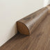 Smooth wooden baseboard in a half-round shape, finished in light wood tones, resting against a neutral wall.